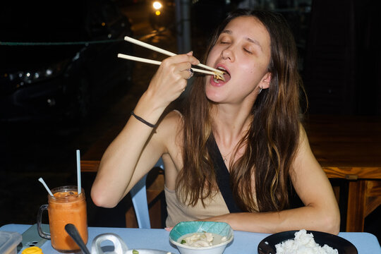Young Woman Eating Asian Street Food with Chopsticks UGC Flash Photo