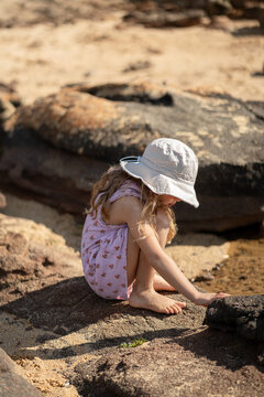 A girl looking for shell and exploring rocks at the beach