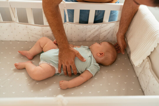 Crop dad putting baby in crib