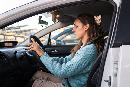 Smiling  woman driving a car, looking at the steering wheel. 