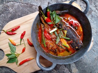 Mangut lele placed in a pan isolated on white background. Dish made from fried catfish, chili, basil, coconut milk and some spices. Yogyakarta traditional dish. Indonesian food.