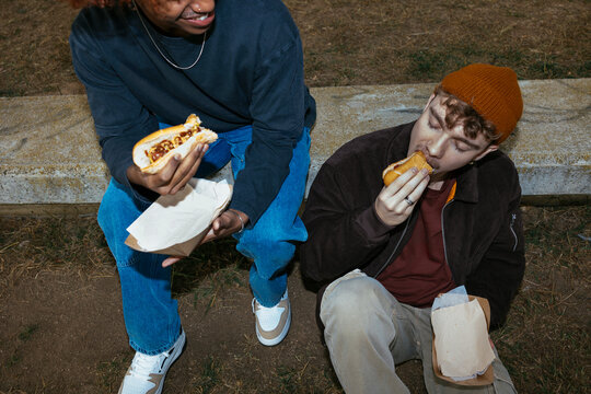 Crop diverse friends eating hot dog ugc