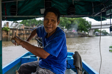 A tour guide steers a longtail boat on the Tapi River in Thailand