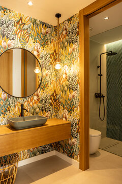 A colorful and eclectic bathroom with a wallpapered wall 