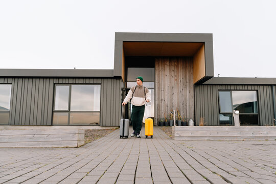 Young traveler man with baggage in front of modern eco hotel