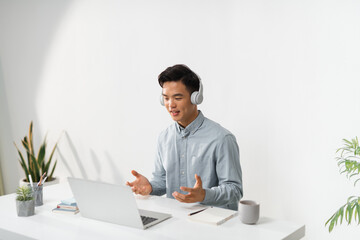 Smiling guy headset gesticulating with hands and watching laptop