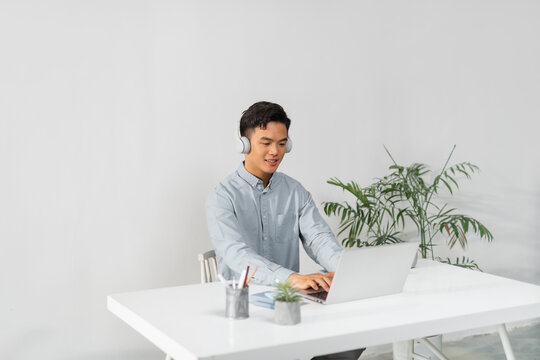 a young man wearing headphones typing on a laptop