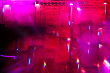 Pink light effects inside empty brick wall room at alternative party