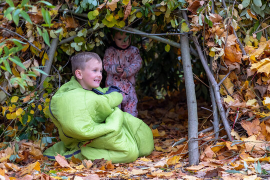 children playing with sleeping bag in an autumn hut
