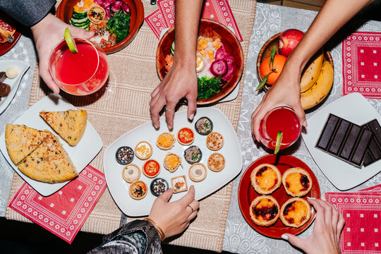 Hands reaching for food at dinner table