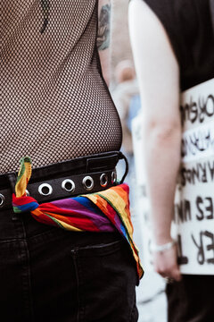 Unrecognisably man with a scarf in lgbt colours tied to his belt
