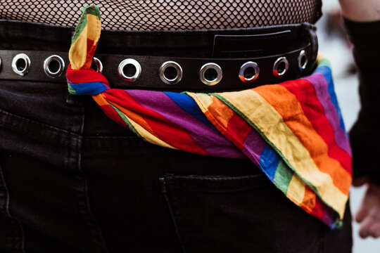 Unrecognisably man with a scarf in lgbt colours tied to his belt