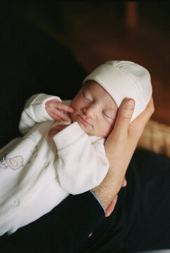 Film photo of a newborn sleeping in father's hands