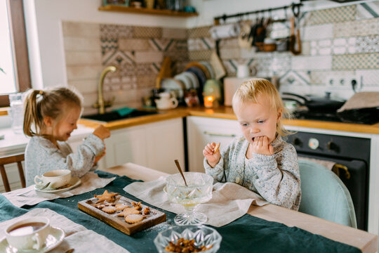 Two little funny sisters eating festive dinner together in the kitchen