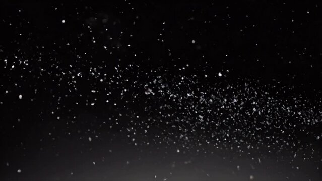 Snow dust against black background. Dynamic motion of white particles