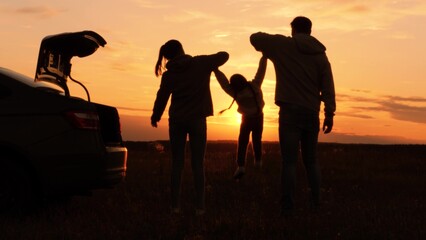 Silhouettes of having fun mom dad kid. Golden sunset, cheerful joyful family at holidays holding...