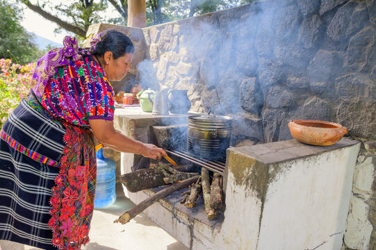 Latin woman lights the bonfire using a branch of the tree known as ocote.
