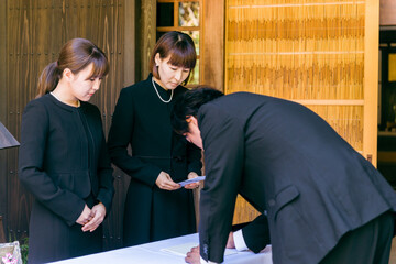 お葬式で芳名録・芳名帳にサインする高齢者の日本人男性
