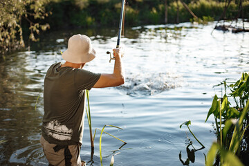 Young fisherman with fishing rod near the lake at summer