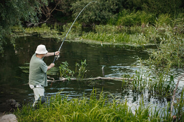 Fisherman with fishing rod near the lake at summer