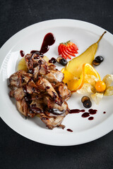 Exquisite teriyaki chicken wings with a side of fresh fruit, elegantly served on a sleek black...