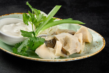 Russian appetizer from salted milk mushrooms with sour cream and onion on dark concrete background. Salted gruzdi in minimal style on black table. Mushroom appetizer on plate. Milk mushrooms.