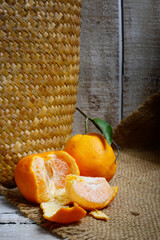 Tangerines or mandarin oranges (Citrus reticulata) are oranges that can grow in tropical and subtropical areas, randomly some are whole, some have been cut, with a natural wood and woven background