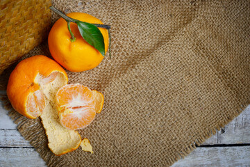 Tangerines or mandarin oranges (Citrus reticulata) are oranges that can grow in tropical and subtropical areas, randomly some are whole, some have been cut, with a natural wood and woven background
