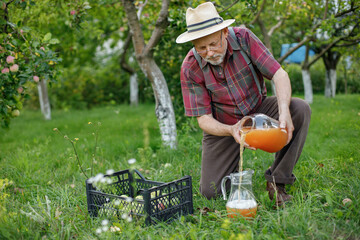 Farmer with a jar of apple juice standing in modern orchard