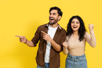 Excited Indian Couple Pointing and Celebrating on Yellow Background