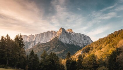 a majestic mountain formation the watzmann in bavaria germany with a colorful sunset sky and woodlands in the foreground - obrazy, fototapety, plakaty