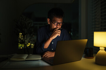 Serious businessman sitting at desk and working late at night .