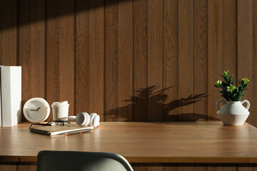 Comfortable workplace with headphone, notebook, coffee cup and houseplant on wooden table.