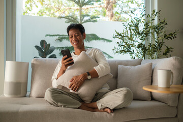 Happy relaxed man sitting on couch at cozy home and using mobile phone.