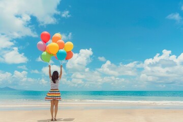 A girl holding a cloud of colorful balloons on a sunny beach - obrazy, fototapety, plakaty