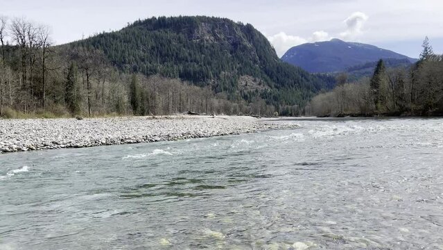 Sauk river with two sections in Washington state cascade mountains during early spring season with clear water and rolling clouds
