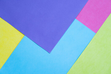 abstract geometric background with pink, blue, green, yellow and purple paper, shot with top view
