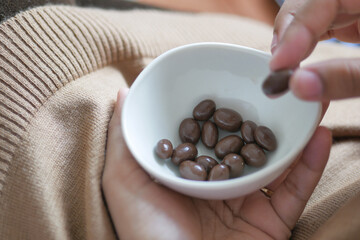 woman hand pick round shape chocolate candy in a bowl 