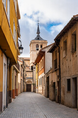 Picturesque alley with the church tower jutting out from the rooftops, Aranda de Duero. - obrazy, fototapety, plakaty