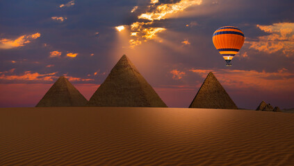 Hot air balloon flying over Giza Pyramid Complex at amazing sunset - Cairo, Egypt