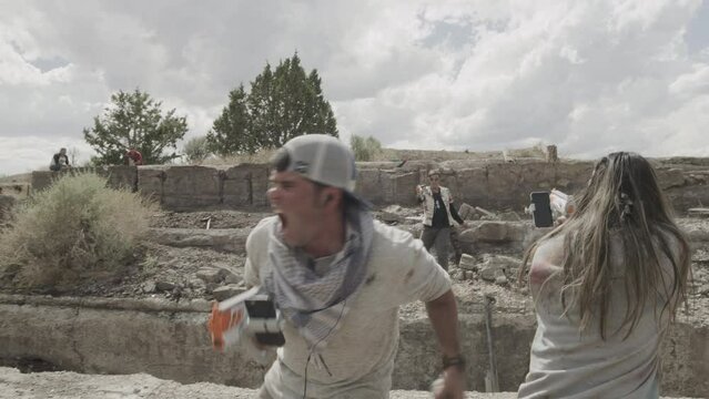 Man and woman fighting off attackers with toy guns in desert