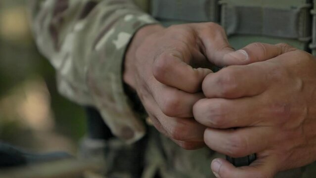 Ukrainian soldier loading 5.56 AR-15 magazine close-up on hands