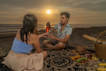 Couple in love having a picnic and toasting with wine on the beach