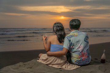 Couple in love embracing, toasting with wine, looking at the sea at sunset