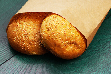 burger buns in a package on a wooden background. appetizing buns with sesame in a paper package	