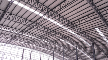 Curve metal roof beam structure with aluminium corrugated steel roof and skylights inside of large industrial factory building, low angle and perspective side view