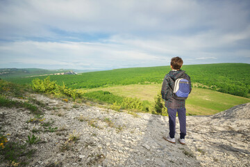 Boy standing and looking at mountainous landscape.
