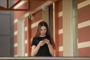Portrait of a young beautiful long-haired girl outdoors in dark clothes.