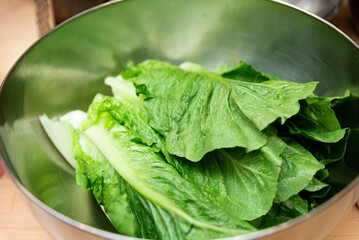 Fresh Green Lettuce in Bowl. A stainless steel bowl filled with crisp, fresh green lettuce leaves,...