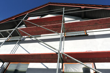 A scaffolding near a wall which is covered with prime before rendering exterior walls, windows and...